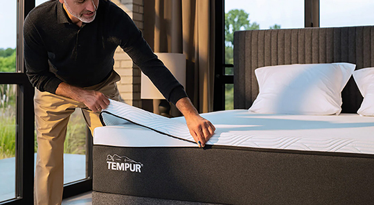 man unzipping a mattress cover on a bed